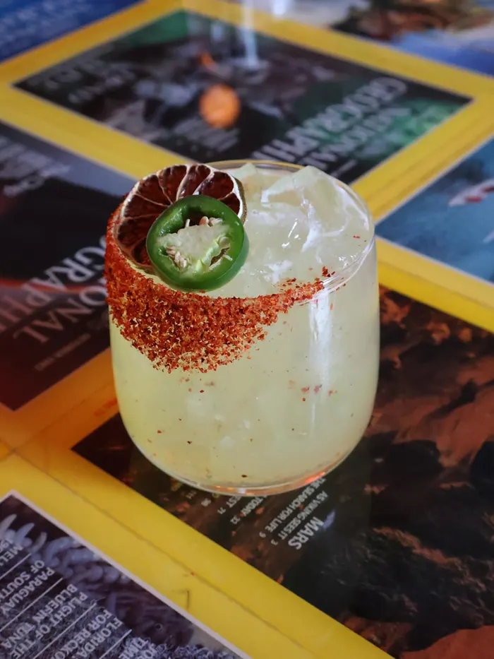 La Piccola cocktail with a chili-salt rim and jalapeño slice on the National Geographic bar top